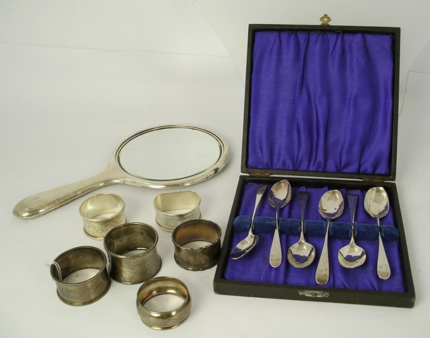 A SELECTION OF SILVER ITEMS comprising; six assorted silver napkin rings, a hand mirror, six