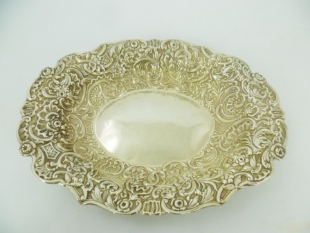 WILLIAM COMYNS A VICTORIAN SILVER OVAL DISH having pressed decoration, plain centre with flora and