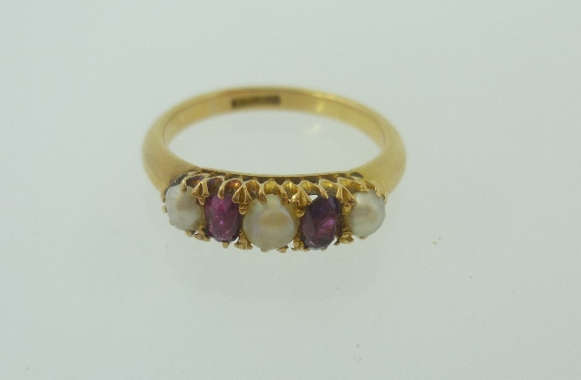 A VICTORIAN 18CT GOLD DRESS RING set two oval rubies and three seed pearls, stamped 18ct, ring size