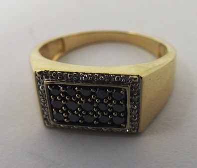 A 9ct GOLD GENTLEMAN`S SIGNET STYLE DRESS RING having tablet shape top set three rows of five black