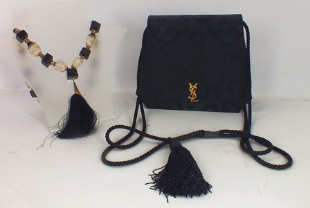 YVES SAINT LAURENT A VINTAGE HANDBAG in black silk with cord and tassel, and a Lucite NECKLACE in