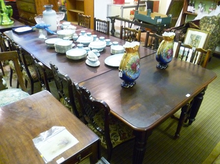 A VICTORIAN MAHOGANY EXTENDING DINING TABLE having twin squared ends with rounded corners, raised on