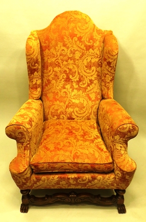 A 20TH CENTURY GEORGIAN STYLE HIGH BACK WINGED ARMCHAIR all over upholstered in a golden floral