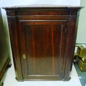 A GEORGIAN OAK HANGING CORNER CUPBOARD having inverted pediment, crossbanded panel door and triple