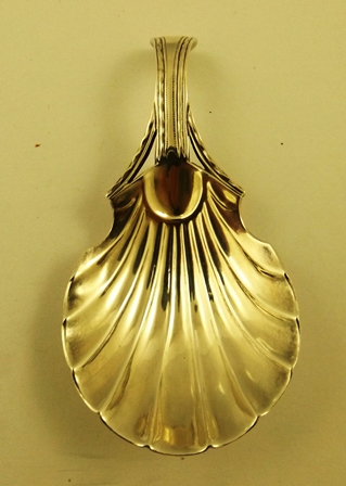 G** S** AN EARLY 19TH CENTURY SILVER CADDY SPOON having scallop bowl and bright cut handle, makers