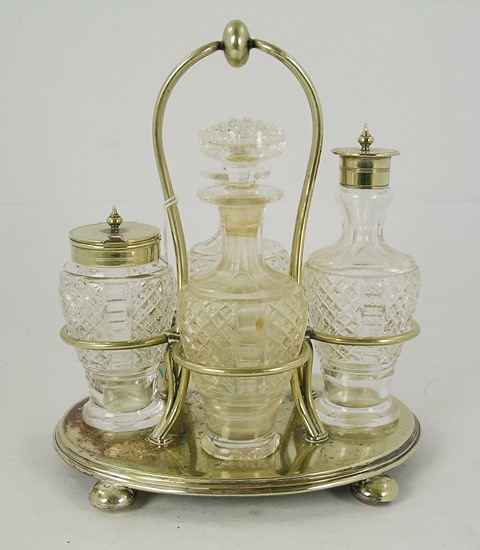 AN EPNS FOUR BOTTLE CRUET having wire frame and oval base, raised on four bun feet