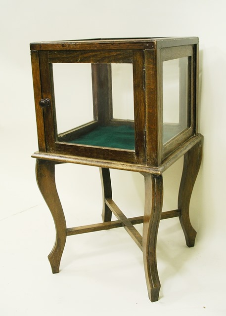 AN OAK FRAMED CUBE TOP DISPLAY CABINET with bevelled glass side panels, baize based with single