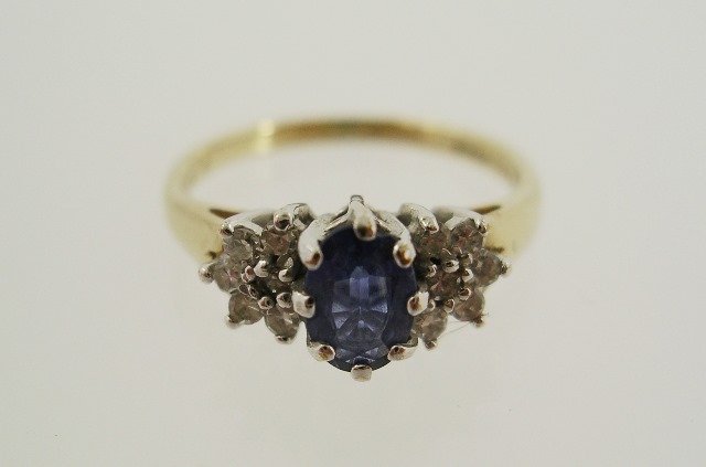 A 9CT GOLD SAPPHIRE AND DIAMOND DRESS RING having oval central sapphire flanked either side with