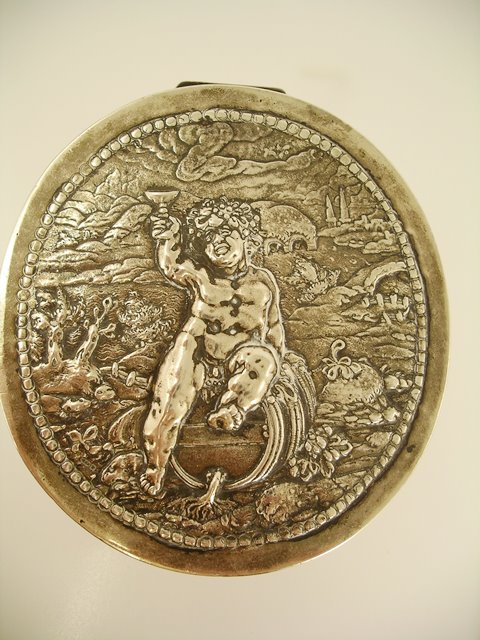 A FOREIGN SILVER OVAL TRINKET/TACK BOX, having repousse worked lid and sides, with Bacchanalian