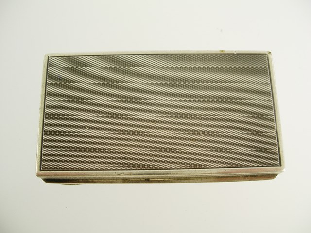 A FOREIGN SILVER COLOURED METAL SNUFF BOX of rectangular form, engine turned with wash gilt