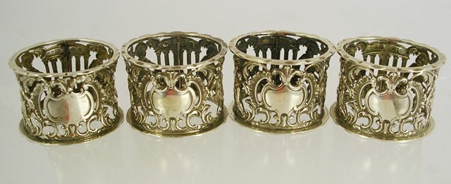 THOMAS HAYES A SET OF FOUR VICTORIAN SILVER NAPKIN RINGS, each fretted and pressed with Bacchanalian