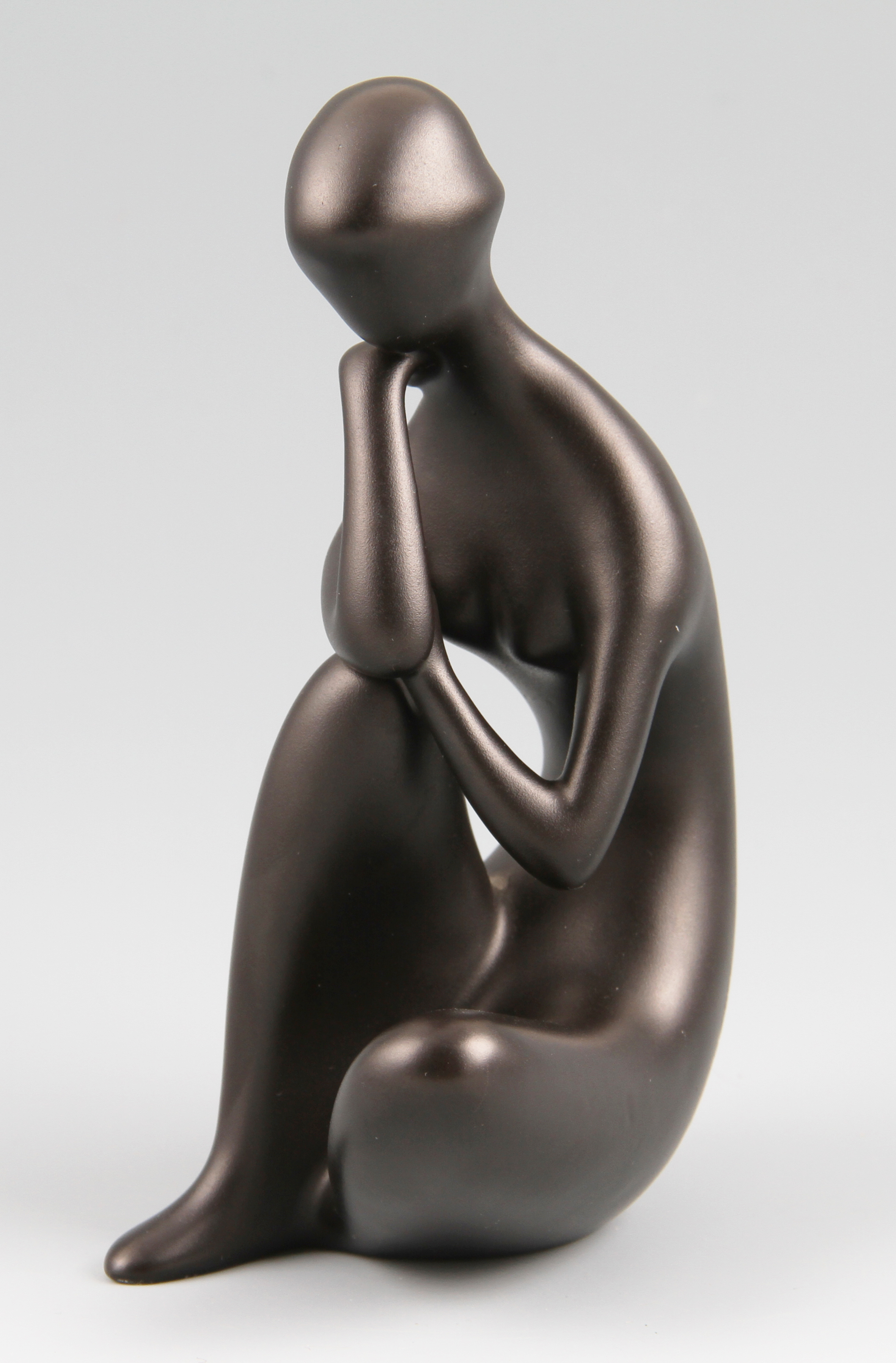 A Royal Dux modernist porcelain figure with black glaze, of a seated woman leaning on one knee,