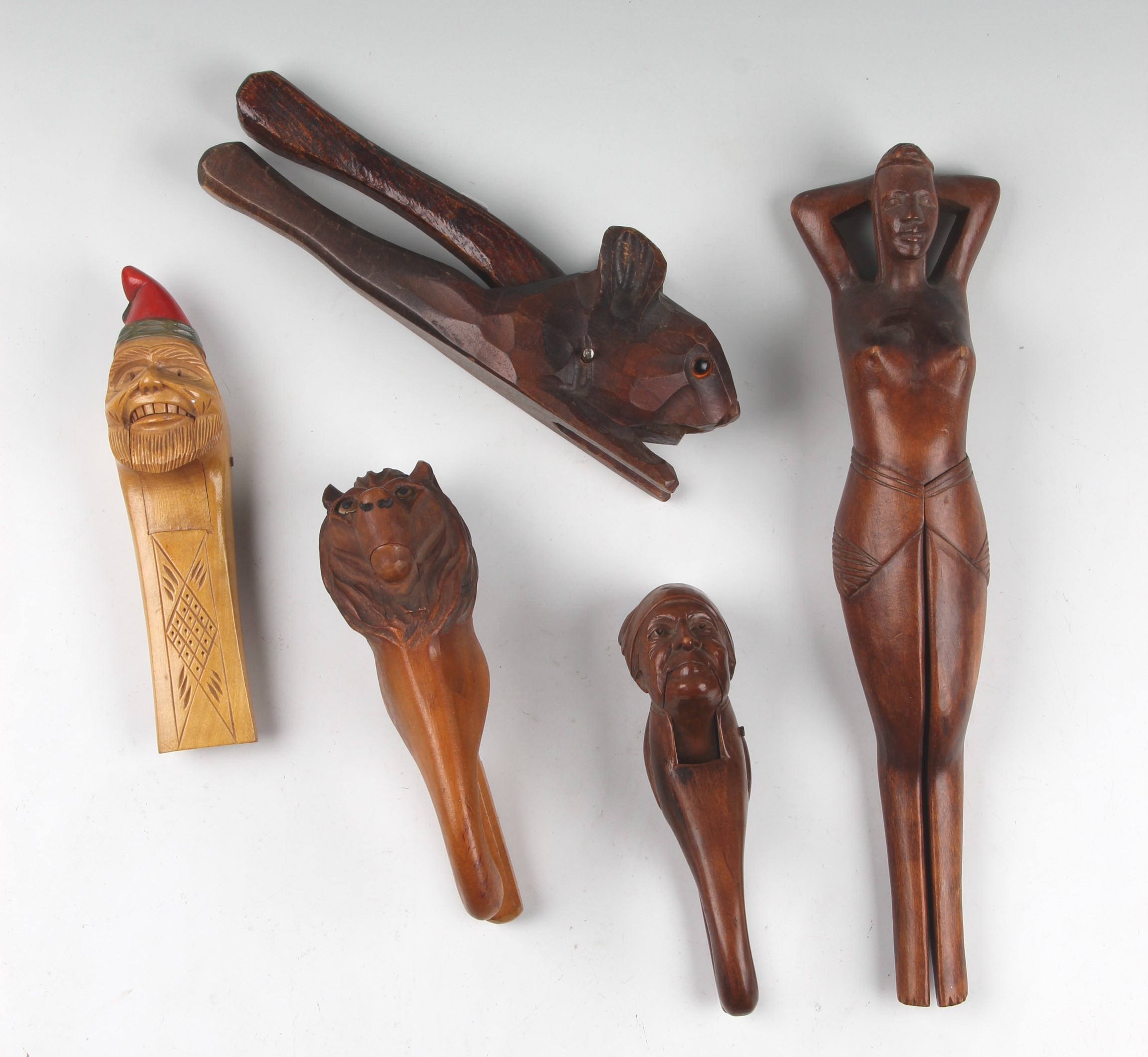 A group of five treen nut crackers to include one in the form of a squirrel with glass eyes, lion,