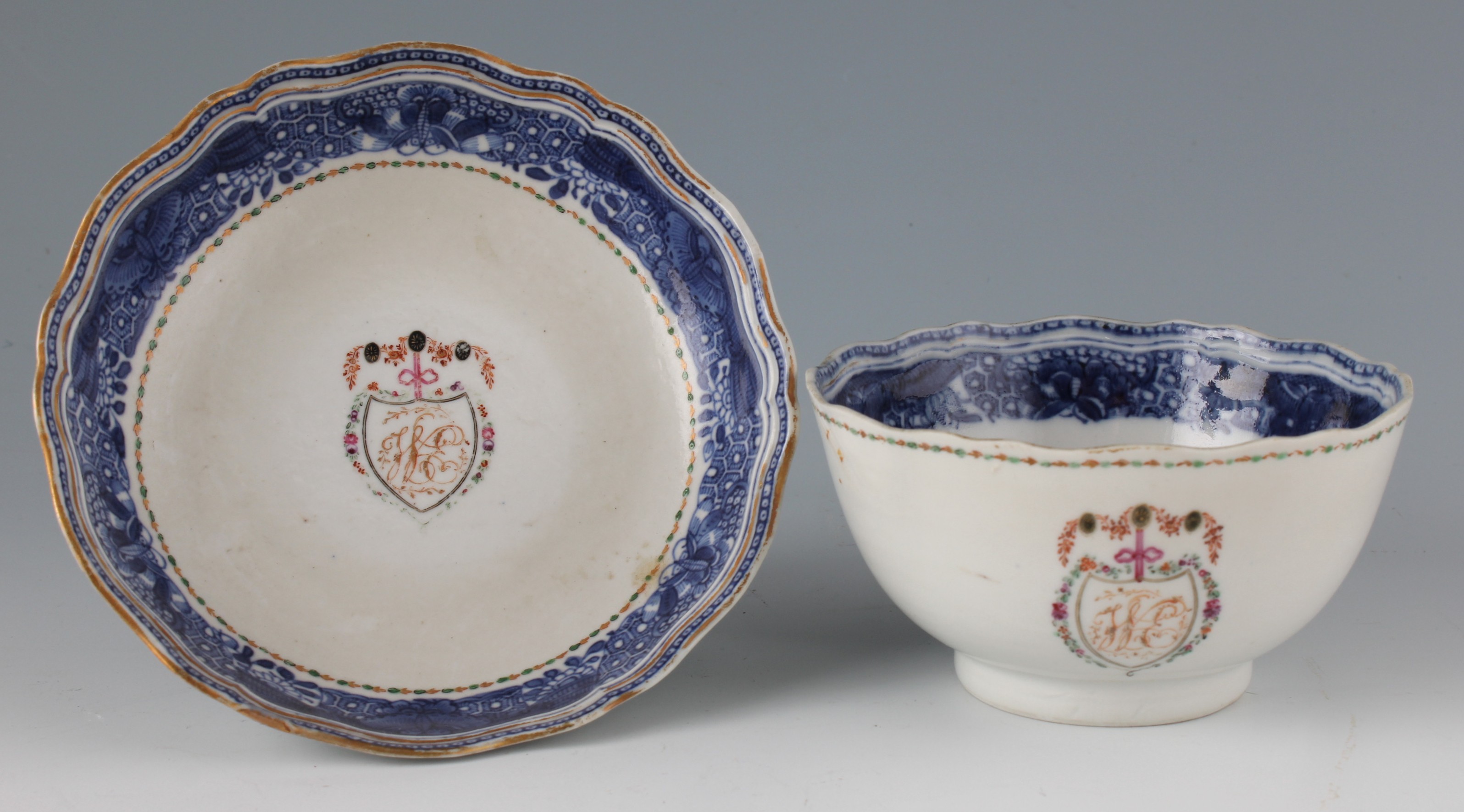 An 18th Century Chinese porcelain armorial tea bowl and saucer, each with gilt scalloped edge and