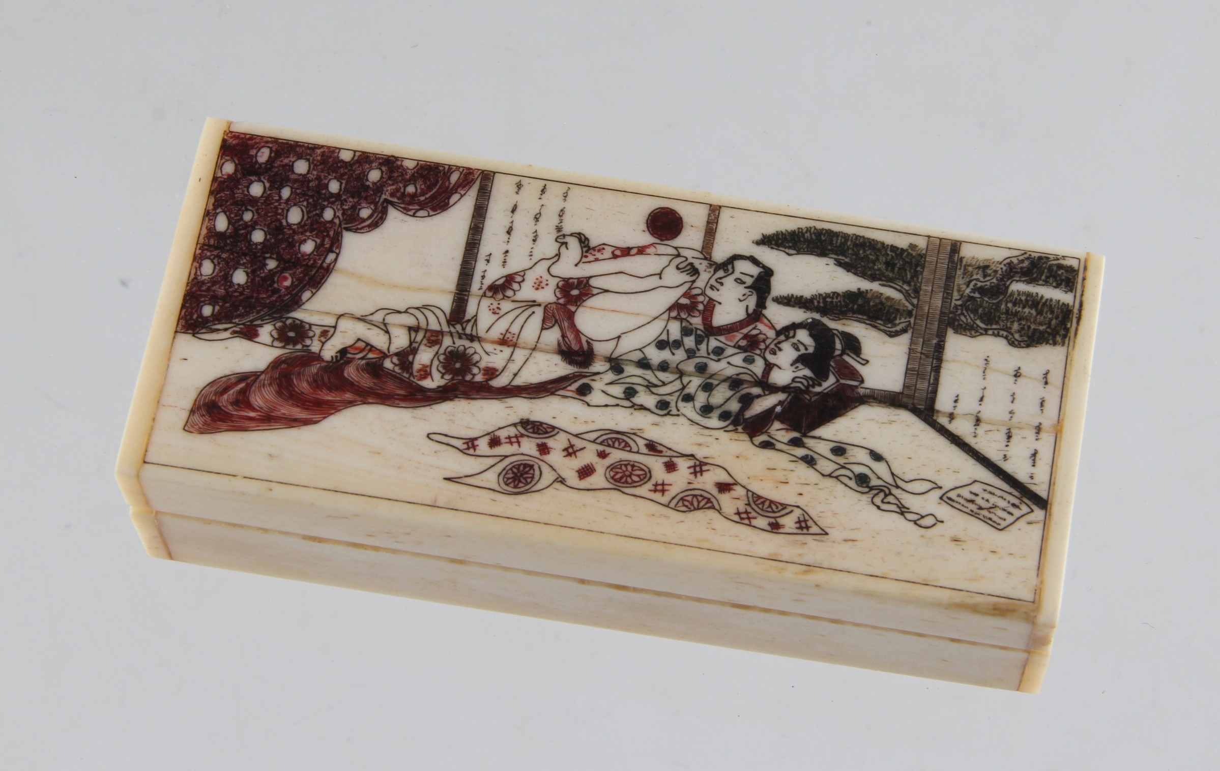 A reproduction bone scrimshaw style box with Japanese style erotic group, approx. 9.5cm long.