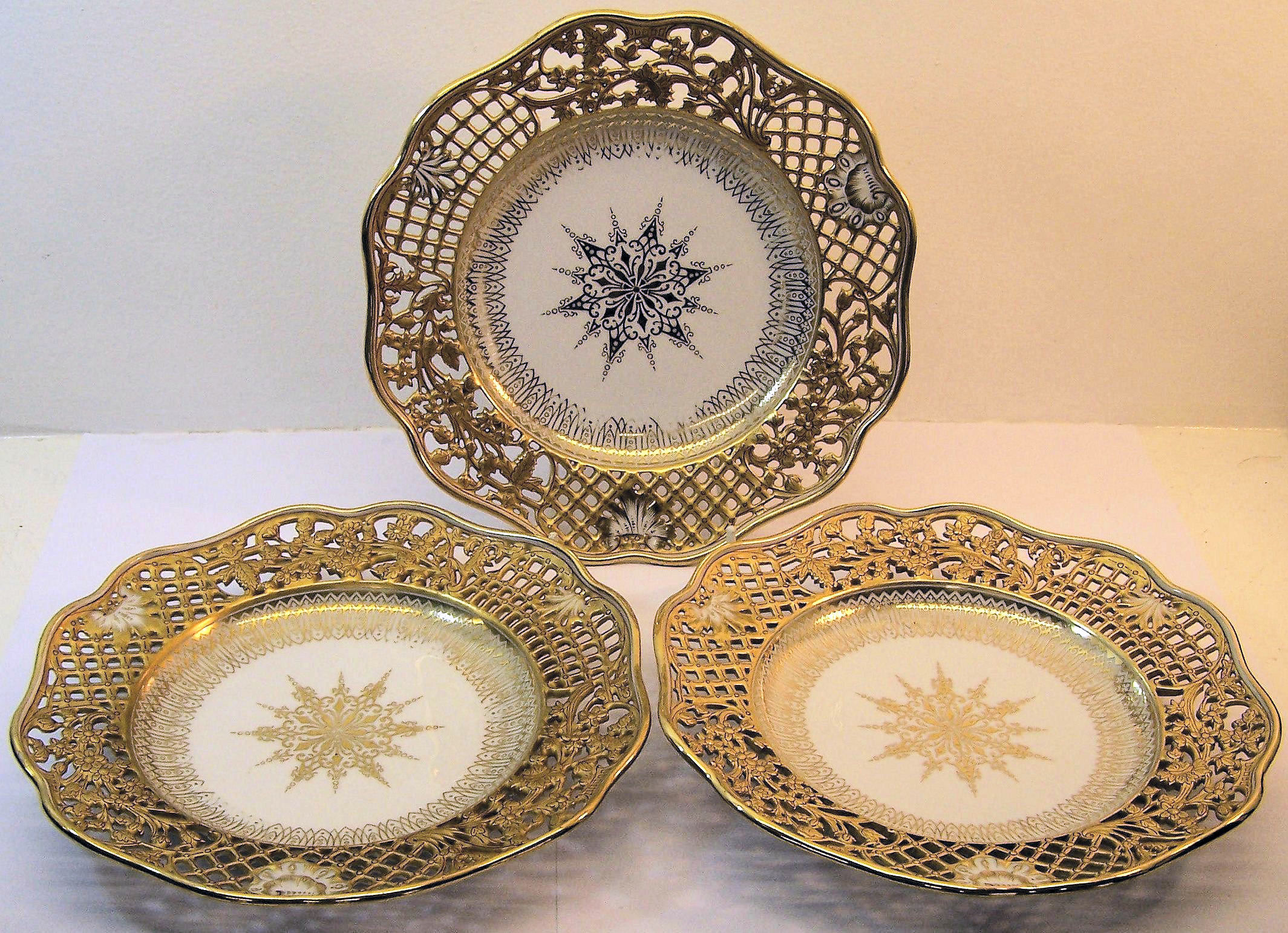 A set of twelve Continental Dessert Plates, the pierced borders decorated in gilt with trailing