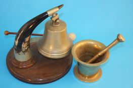 A brass pestle and mortar and a wall mounted brass bell hanging from a horn.