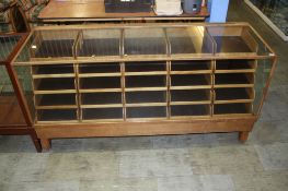 A glazed haberdashery cabinet with glass top, sides and front with 5 rows of 5 drawers. 183 cm