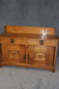 An oak Arts and Crafts sideboard with raised back, two short drawers below two panelled doors,