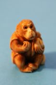 A carved netsuke of a seated monkey.