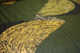 A large roll of woven wool fabric on a green ground with abstract shell pattern. Approx. 35m plus