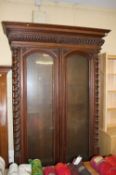 A Victorian oak bookcase with moulded and gadrooned cornice below two arched glazed doors flanked by