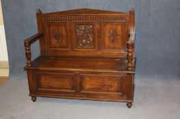 A 20th century oak settle with 3 panelled carved back with lift up seat below two panels to the