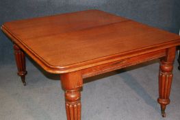 A Victorian mahogany dining table with two leaves, supported on turned fluted and tapering legs,