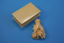 A small bone box containing a bone brooch of a hand holding flowers.