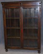 An early 20th century oak bookcase with astragal glazed doors supported on bun feet. 116 cm long