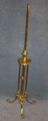 A brass telescopic standard lamp supported on curving scrolled legs.