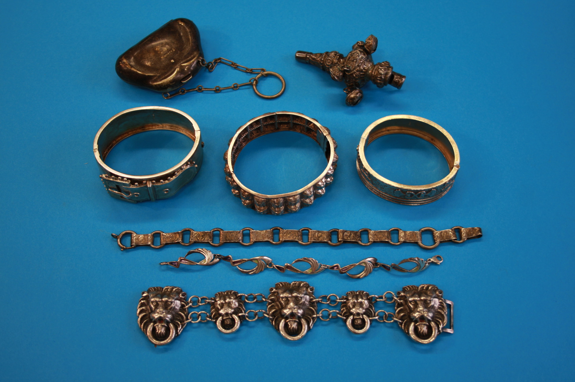 Two silver bangles; a silver baby`s rattle; an EPNS purse; a lion mask silver coloured bracelet; a