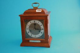 A reproduction mahogany mantle clock by Smiths with stepped top, silvered and brass dial, supported