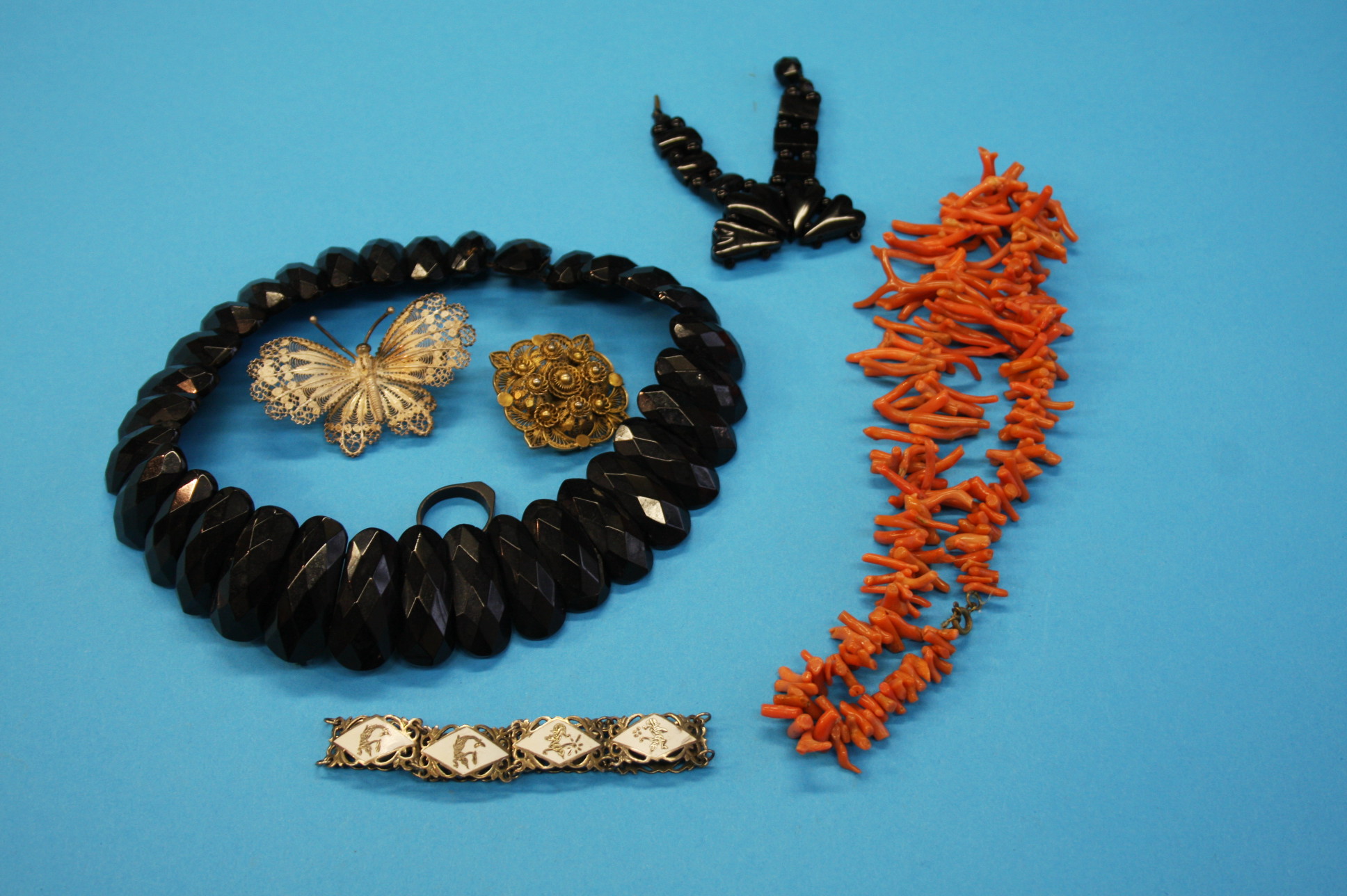 An orange coral necklace; a jet coloured necklace, bracelet and ring and an insect brooch etc.