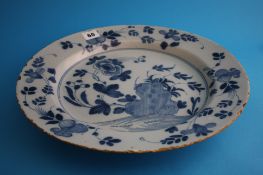 An 18th century tinglaze earthenware blue and white charger decorated with trees and flowers. 36 cm