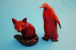 A Royal Doulton flambe seated fox, 11 cm high; and a Penguin, 15 cm high, printed marks.