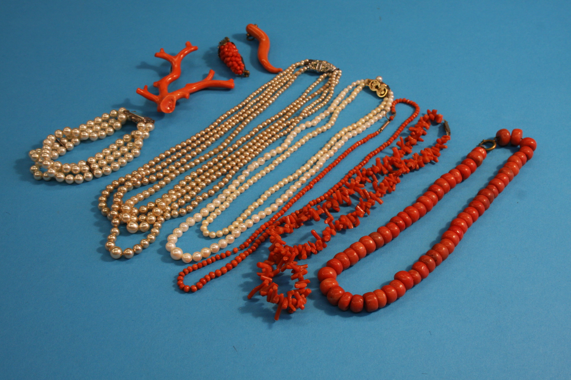 A quantity of orange coral necklaces, brooches etc, and various pearl necklaces. Please note large