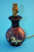 A modern Moorcroft table lamp decorated with red and blue anemones on a dark  blue ground,