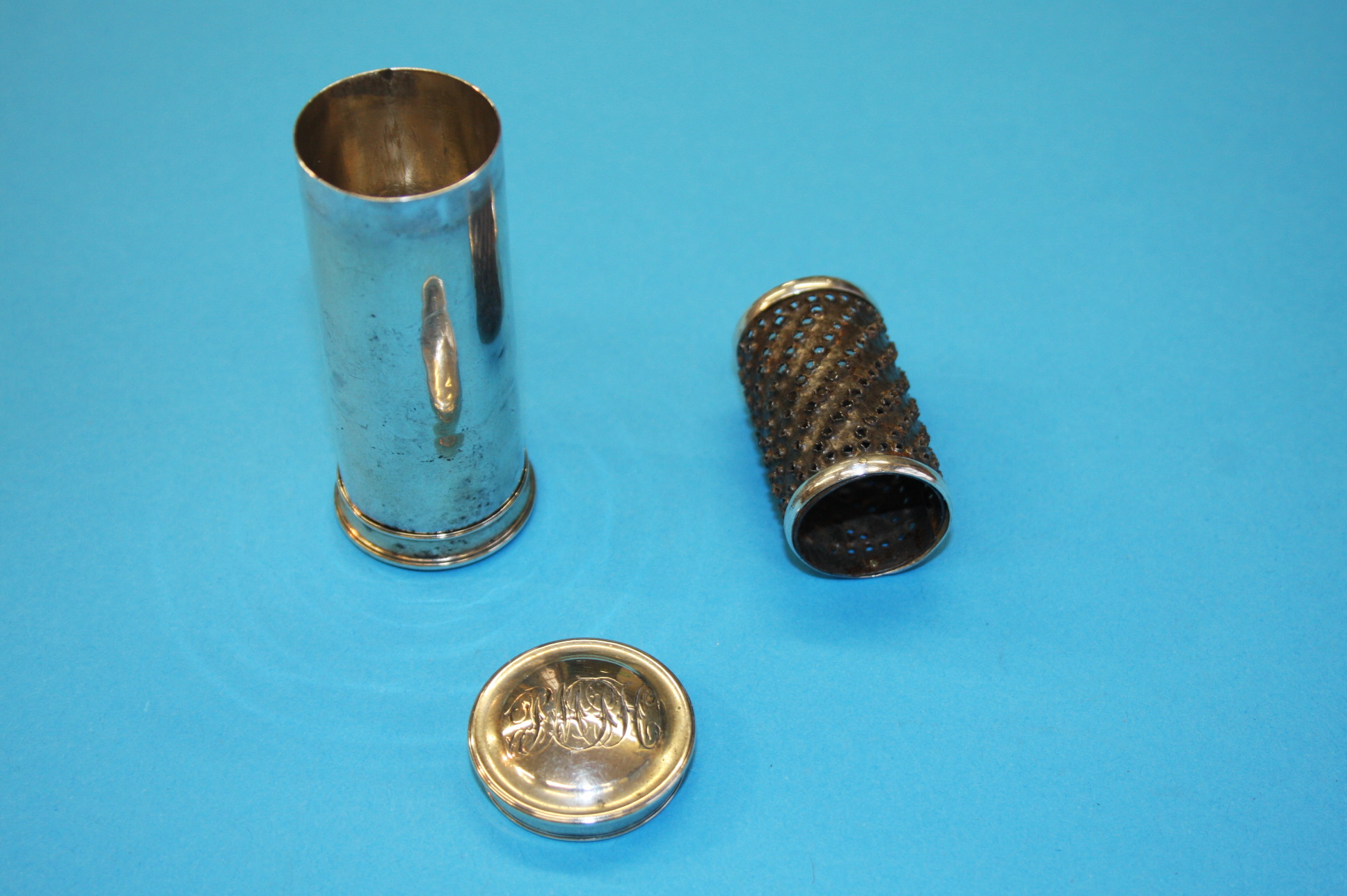 A silver nutmeg grater cylinder with capped double ends, one end holds the grater and the other the