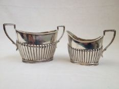 Late Victorian silver cream jug and sucrier with half gadrooned bodies and angled handles,