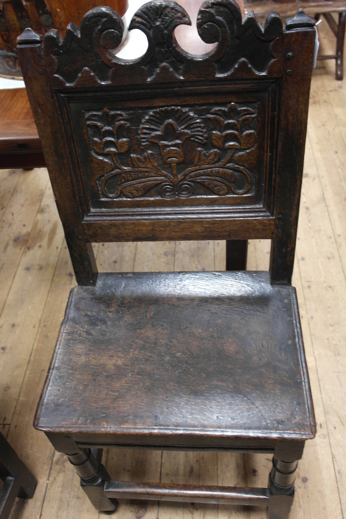 A 17th Century and Later Oak Chair:
the shaped back carved with flowers and foliage on turned