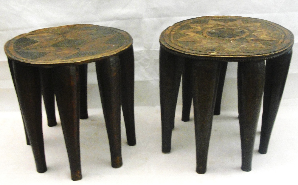 A Pair of African Lobbe Tribal Stools:
the circular tops carved with geometric designs on nine
