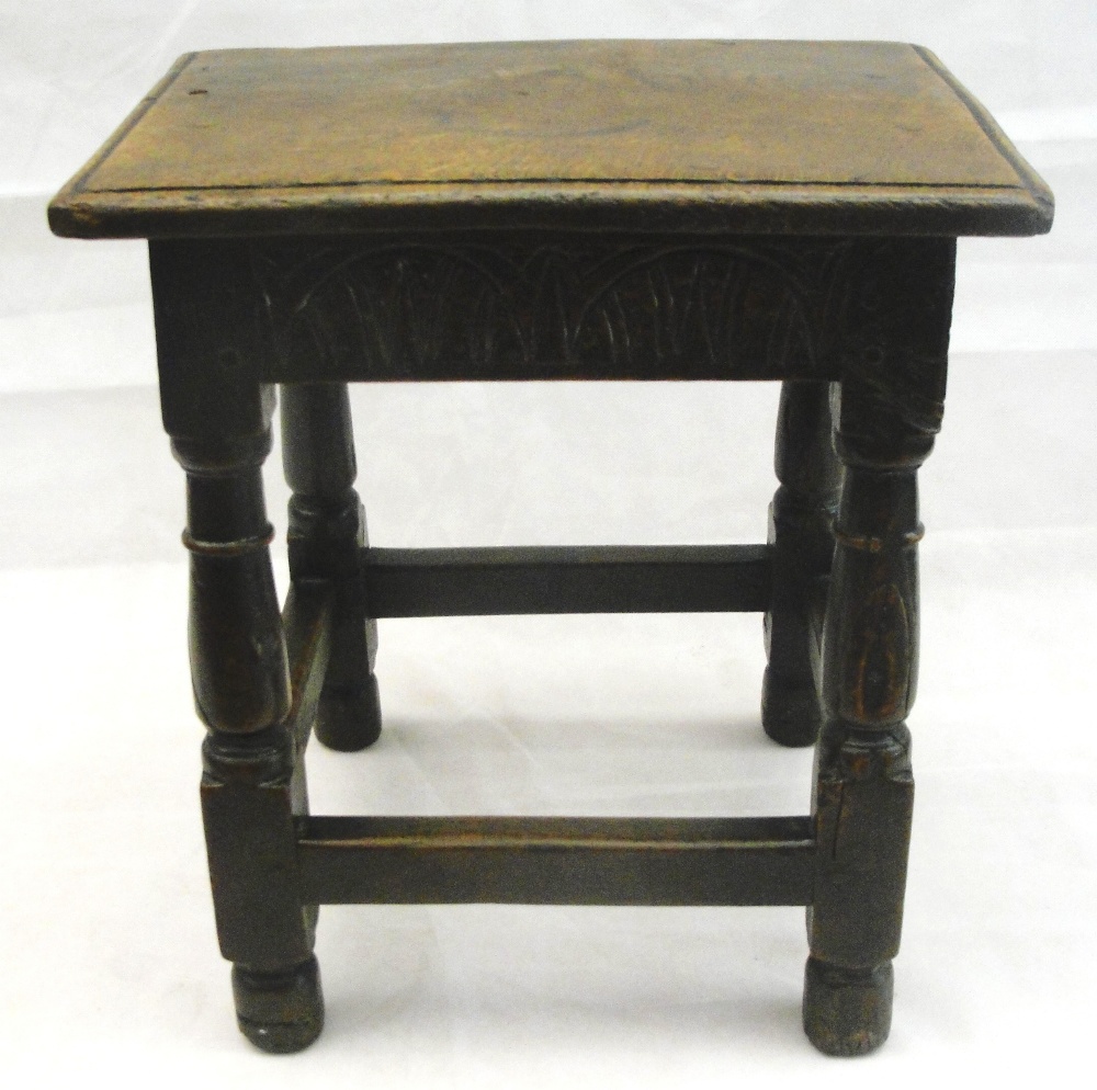 A 17th Century Oak Joint Stool:
the rectangular top above a carved lunette frieze on turned and