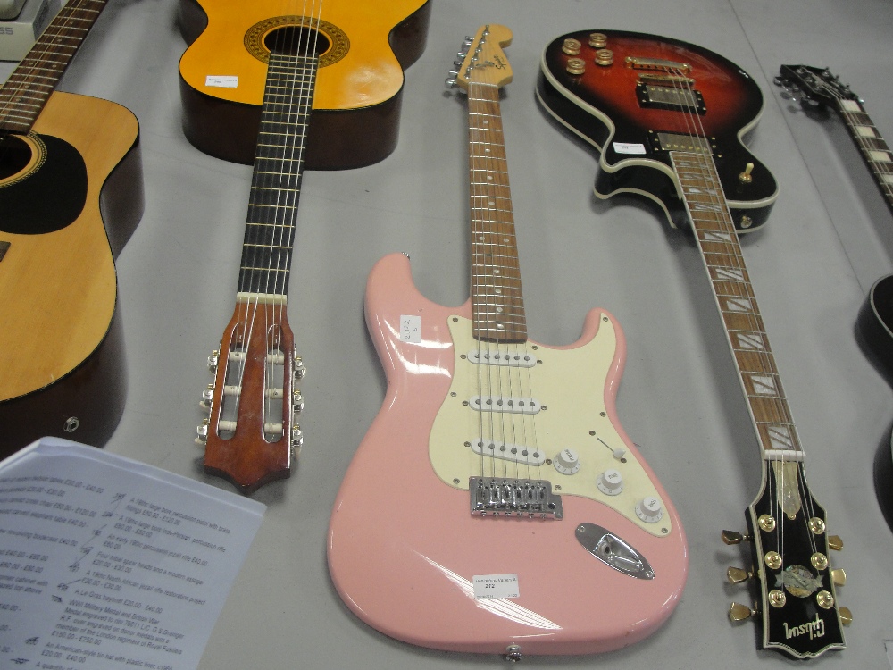 A Squier pink electric guitar, signed and numbered to neck fender
