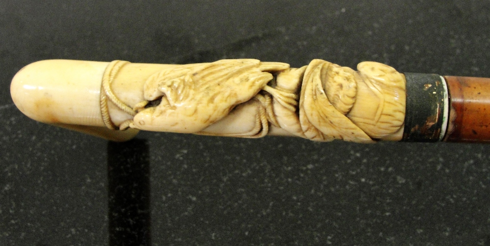 An 19th century ivory handled walking stick:  
Carved with hunting hawk with hood on arm of 18th