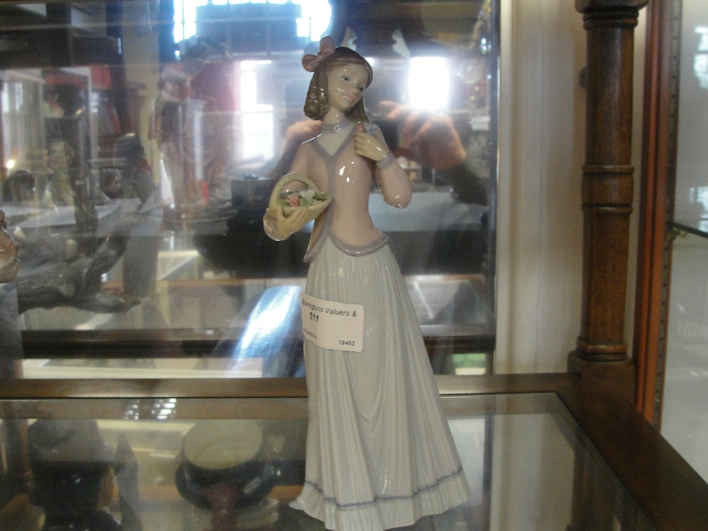 A Lladro figure of a girl holding flowers