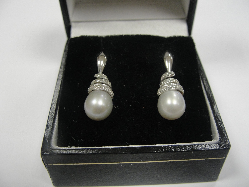 A pair of 9ct and diamond swirl set pearl earrings