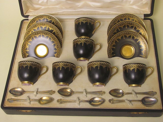 A cased Royal Worcester coffee set comprising six cups and saucers with gilt work on a black ground