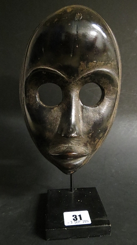 A Dan tribal art Gunyeya mask, West Africa with large round pierced eyes and black patination,
