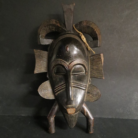 A carved wooden tribal art Kpeliye mask, Senufo peoples, West Africa with pierced eyes and a good